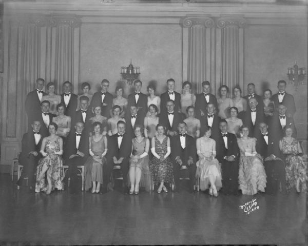 Group portrait of Triangle Fraternity brothers and dates at the spring formal in the Crystal Ballroom, Loraine Hotel.
