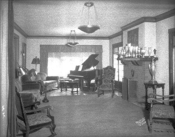 Phi Kappa Tau living room showing trophys and baby grand piano, 615 North Henry Street.