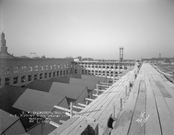 Elevated view of the University of Wisconsin Mechanical Engineering Building, under construction, showing workers on the roof, 1513 University Avenue, looking north across the roof.