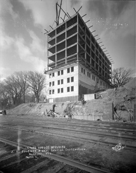 View across railroad tracks towards the State Office Building, 1 W. Wilson Street, under construction.