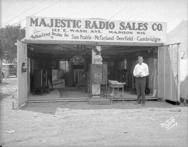 Salesman standing in front of Majestic Radio Sales Co., (122 E. Washington Avenue), with a booth at the Dane County Fair.