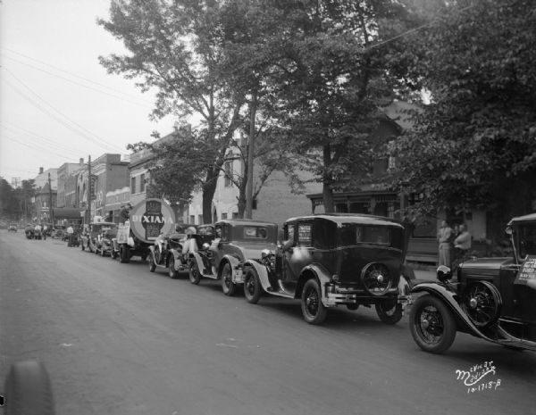 Automobiles and Chanticleer Band on back of a truck in a parade in the 300 block of East Johnson Street for the movie "Dixiana."