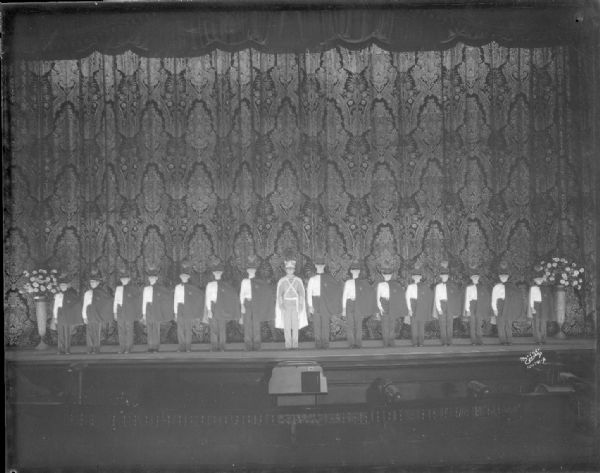 Elevated view of Floyd's Singing Cadets. The cadets and leader are on stage in front of the theater curtain.