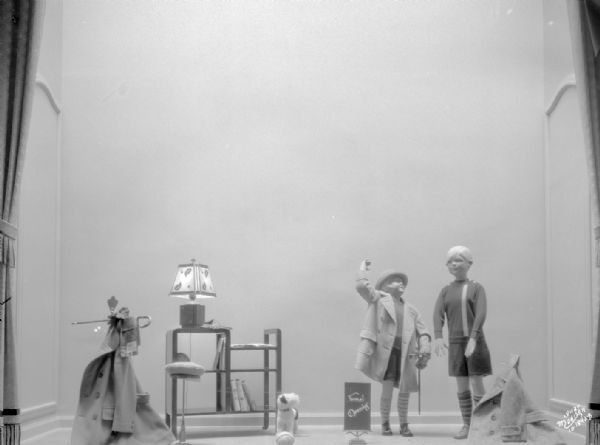 Manchester display window showing two child mannequins with hats and coats.