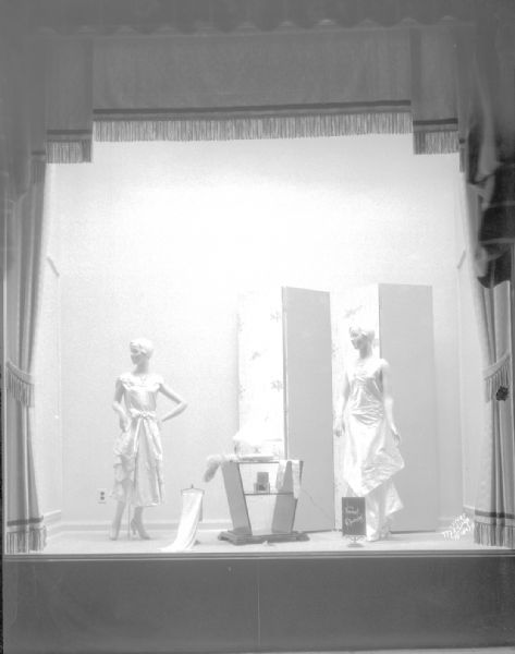 Manchester display window showing two women mannequins in formal dresses.