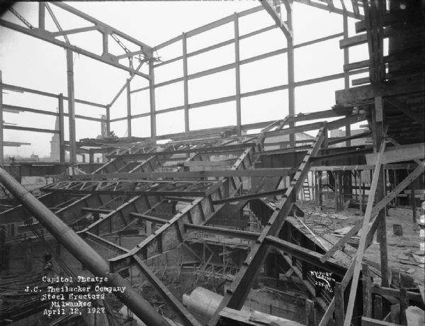 Steel frame of the Capitol Theatre, early in its construction. The steel work was done by J.C. Theilacker Co. Milwaukee, American Bridge Company. A church steeple is in the distance on the left.
