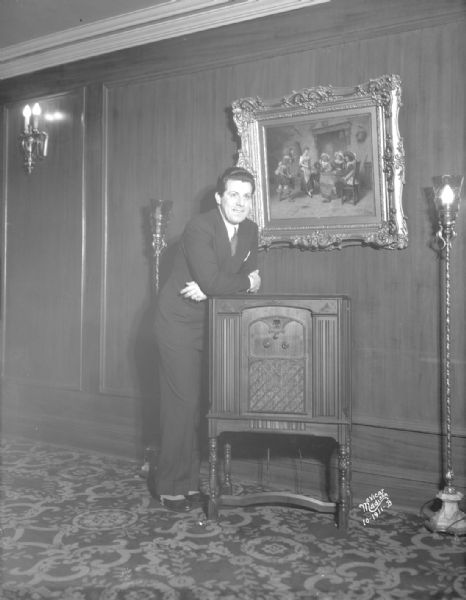 Singer, James Regan, standing by a radio in the Orpheum Theatre, 216 State Street.