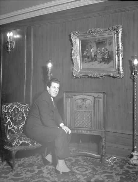 Singer, James Regan, sitting by a radio in the Orpheum Theatre, 216 State Street.