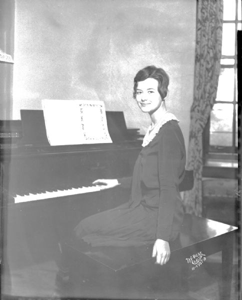 Elsie Onsrud, from Stoughton, national 4-H champion sitting at a piano. She was chosen as 1930 typical 4-H girl, at the National Dairy Show in St. Louis.