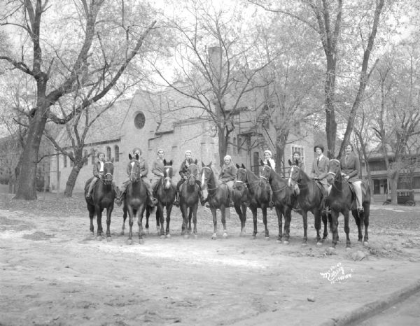 Seven children and two adults are sitting on horses in front of the Blackhawk Riding Academy, 1019 Conklin Place.
