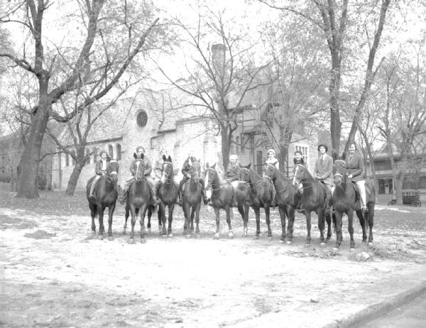 Seven children and two adults sitting on horses in front of the Blackhawk Riding Academy, 1019 Conklin Place.