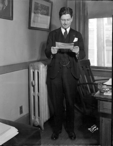 Governor elect Philip La Follette standing and reading a telegram at La Follette headquarters.
