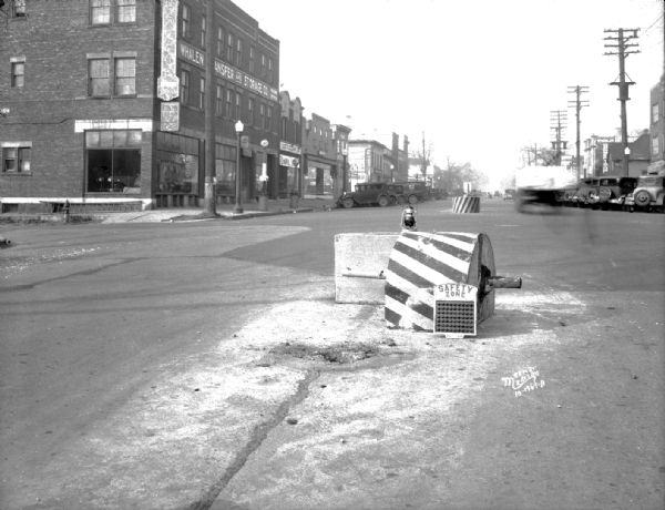 A tipped over safety zone on University Avenue at the intersection at Frances Street. Shows Whalen Transfer & Storage, 605 University Avenue, Blackhawk Electric, 607 University Avenue, Frank Brothers Grocery, 609 University Avenue.