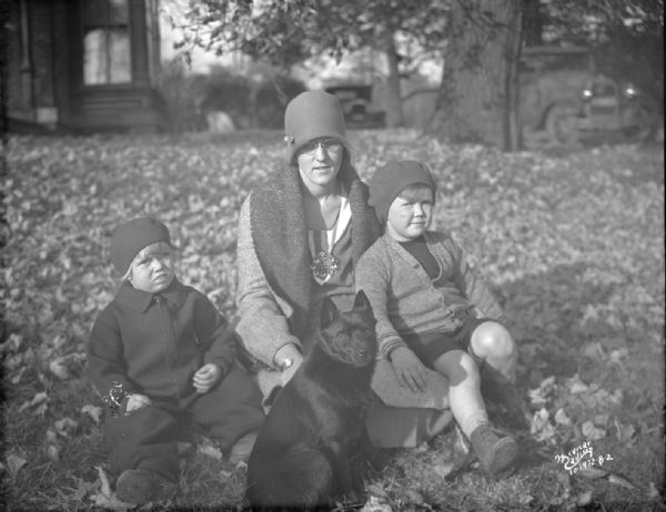 Isabel La Follette (Mrs. Phillip F.)  with her two children, Judith La Follette, Robert M. La Follette III, and their dog, Skip, on the lawn.