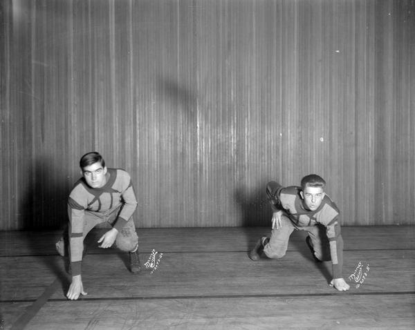 Two football players in uniform on East High School stage. 2093B-1 = Lindgren. 2093B-2 = Miller.