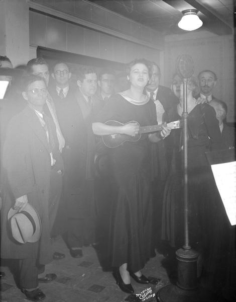 Bessie and Bata Kappelle singing at WISJ radio station in front of microphone with Ole Olsen & Chic Johnson. The woman on the left is holding a ukulele. This was a benefit for the Empty Stocking Fund.