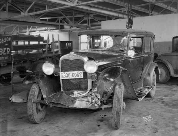 Front view of Arthur Bartz's wrecked Ford automobile parked indoors in a building.