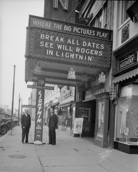 Advertisement for Movie "Lightnin'" starring Will Rogers. The marquee at the Strand Theatre reads: "Break all dates — see Will Rogers in Lightnin." 16 E. Mifflin Street. Two men are standing under the marquee. There is also a Millinery sign on the storefront next door on the right.