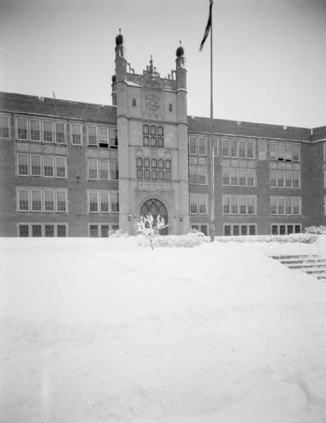 View across snow-covered lawn and steps towards the East High School entrance tower after a snowstorm.