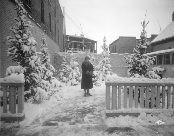 View of Mrs. Piper standing in the garden of Piper's Garden Cafeteria, 120 E. Mifflin Street, after a snowstorm.