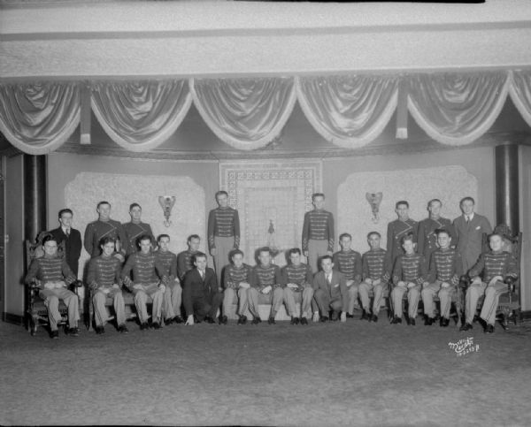 Group portrait of Capitol and Orpheum theater staff and ushers in uniform, standing and sitting around the Capitol Theatre lobby fountain.