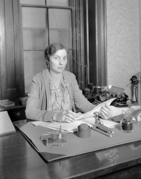 Beatrice Lampert, assistant city attorney, sitting at her desk with telephone and typewriter.