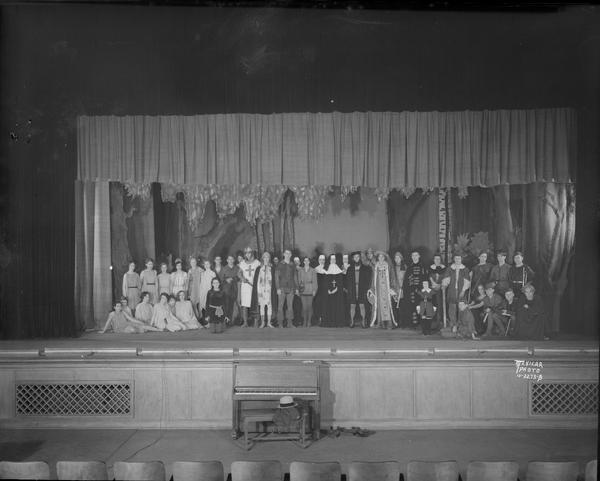 Group portrait of East High School play cast for "Sherwood" in costume on stage.