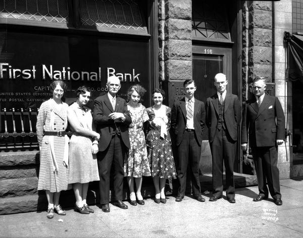 First National Bank of Edgerton officers, who witnessed robbery, posing and standing outdoors in front of the bank.