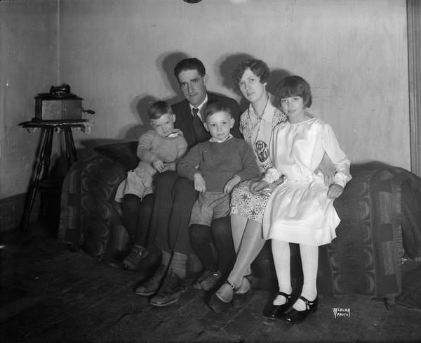 Group portrait of Ernest Kalar, his wife, and three children. There is a Victrola phonograph on a table in the background on the left.