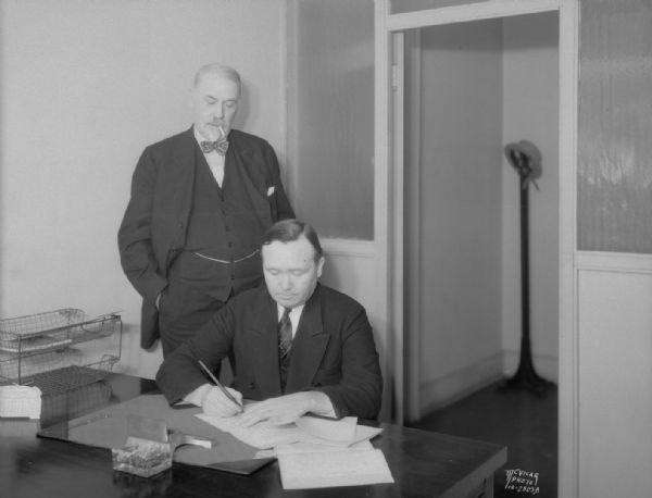 Joseph Conlin, tenor, signing a contract to perform at the Parkway Theater. Dr. William G. Beecroft shown standing is sponsoring Mr. Conlin's appearance.