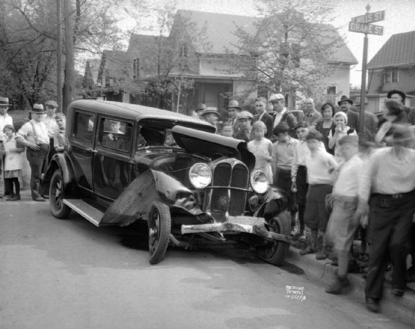 Damaged automobile, driven by Geraldine Annen, going west on Drake Street, and crowd at the corner of Drake and Mills Streets.
