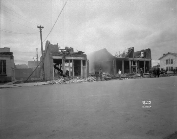 Fire scene from the east end, showing ruins of the Lins and Hood hardware and furniture store, a pool hall and confectionery store, with adults and children looking on.