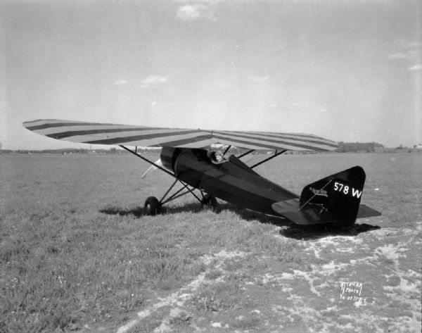 Three-quarter view from left rear towards the "Keen-Ship" airplane parked on a field, with Charles F. Keen, pilot.