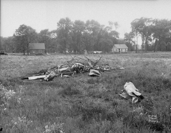 Official coroner's view of Travelair biplane crash at Madison Airport with buildings and cars in the background. Lawrence Fishnich, pilot, and two passengers, Edward Raftree and Edward Breiby were killed.
