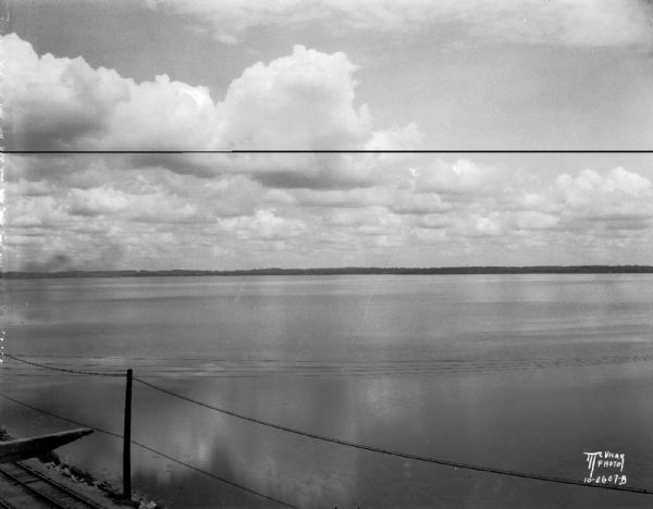 Clouds over Lake Monona. Railroad tracks are in the foreground on the left. The far shoreline is in the distance.