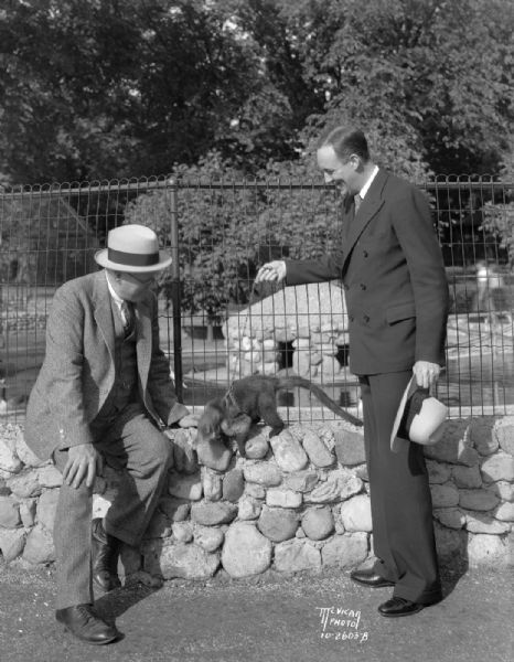 Jim McWilliams, "Pianutist" vaudeville actor, and Fred Winklemann, Zoo director, with the Mexican Snookum bear (coati), at Vilas Zoo (Vilas Park Zoo).