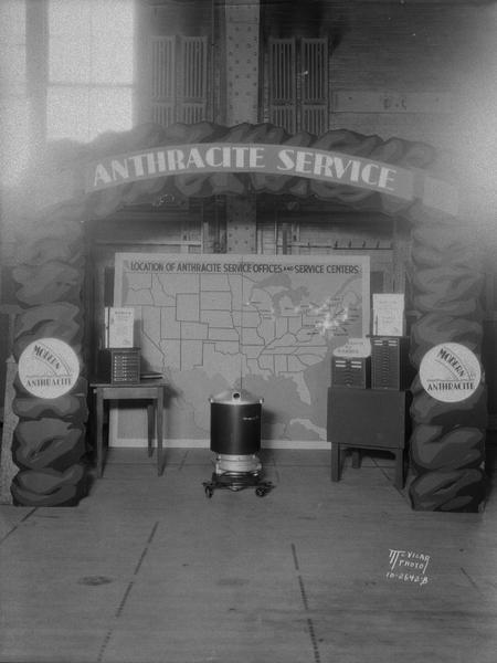 Anthracite Service Booth at Coal Convention, U.W. Armory, with a map of the United States and various service centers. There is a coal stove on display.