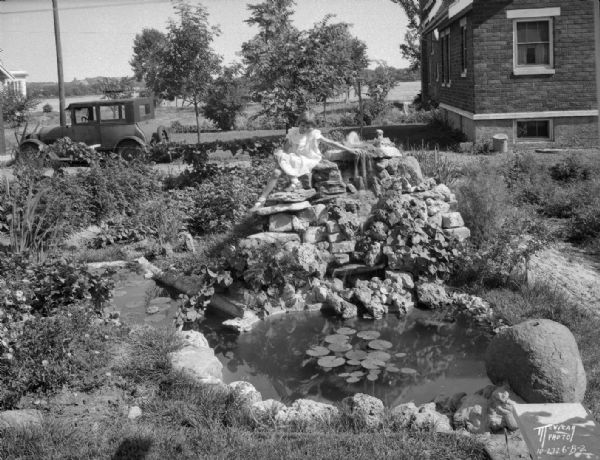 Girl sitting in Arthur G. Clemens rock garden made with stones from every county in southern Wisconsin. Also includes pond, 706 W. Lakeside Street.