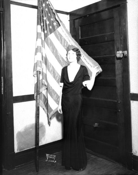 Bernice Hotmar, contestant for the Disabled American Veterans Aviation Ball queen, posing standing with an American flag.