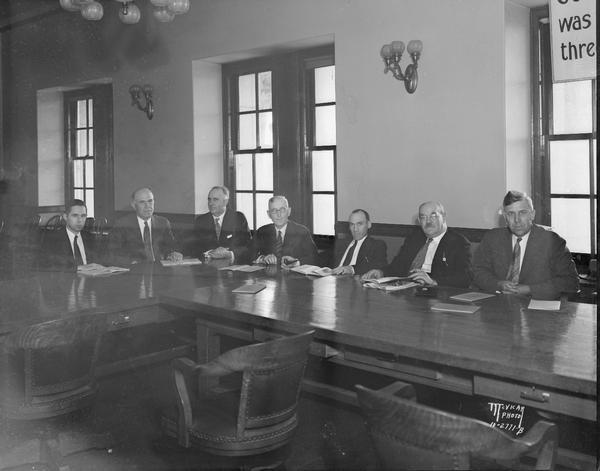 Interim unemployment committee, with seven men sitting around a table.