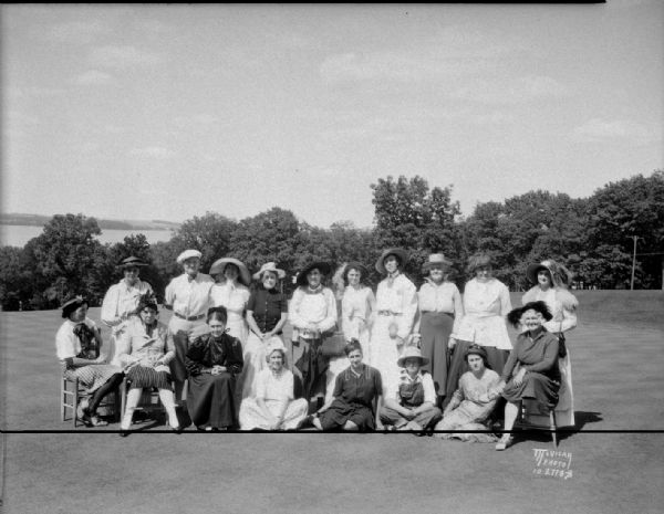 Group portrait, taken outdoors, of twenty women in antique costumes competing in a style show at the Blackhawk Country Club, 3606 Blackhawk Drive.
