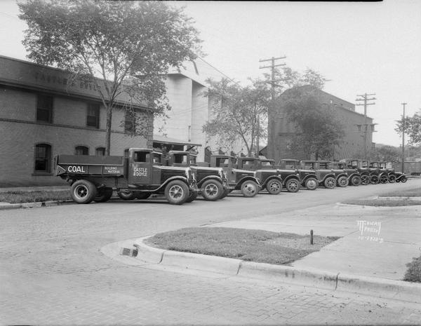 Lineup of 14 White coal trucks from Castle & Doyle yards corner of Monroe and Regent Streets? Negative sleeve reads: "323 W. Johnson Street."