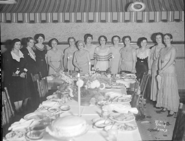 Epsilon Sigma Alpha, national educational sorority, business women's dinner.  Group portrait of thirteen women standing behind a dinner table. The event was held at Belmont Tavern, 31 N. Pinckney Street.