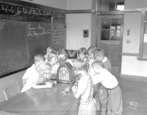 Emerson School children standing by a radio on a table, listening to a broadcast of "The Hare and the Lion," 2421 East Johnson Street.