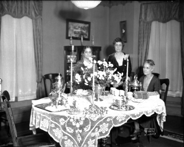 Table set for tea party, benefitting the scholarship fund of the University League, at Mrs. Emma Ogg's home, 1715 Kendall Avenue. L-R: Anne Birge, Emma Ogg, Mabel Sellery.