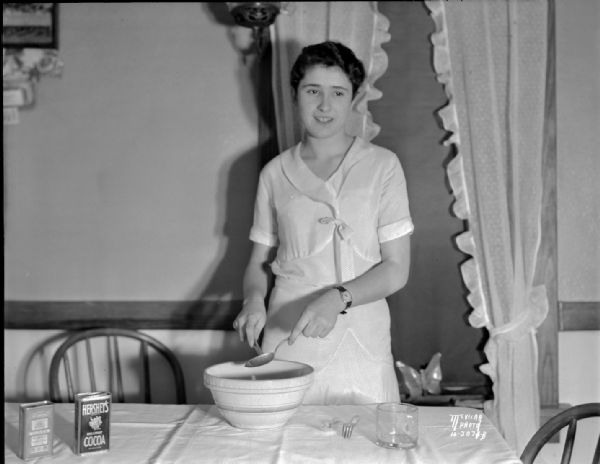 Marian Dolan, of the Maple Knoll 4-H club north of Sun Prairie, 1931 National 4-H champion, making a cake. Shows a Hershey's Cocoa can.