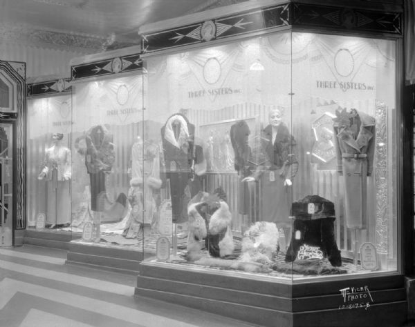 One-half of entry window for the Three Sisters clothing store, 27 S. Pinckney Street, Tenney Building. The window features women's clothing, and are decorated in Art Deco style.
