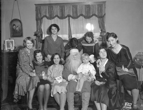 Group portrait of Leona Wasley's card club's Christmas party, with Aldro Wasley dressed as Santa Claus holding a child.