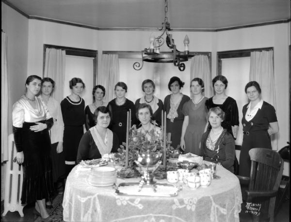 Junior Division (of the University League ?) tea party at the home of Abigail Rundell 2227 Van Hise Avenue. Left to right: Mrs. Russell H. Fitzgibbon, Lila Mortenson, Margaret Cole, Mrs. C.M. James, Dorothy Paul, Mrs. Karl P. Link, Josephine Annin, Mrs. Charles Alexander, Cora Pruess, Marion Winans; and seated, Vangel James, Abigail Rundell and Alice Kundert.