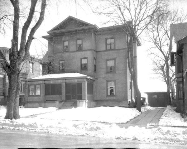 Three-story apartment house, 145 W. Wilson Street, with snow on the ground.